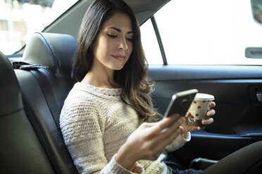 Junge Frau benutzt Smartphone im Taxi - CAVF32797