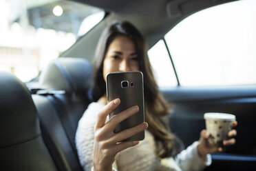 Junge Frau fotografiert mit ihrem Smartphone im Taxi - CAVF32798
