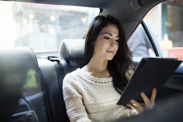 Young woman using tablet computer in taxi - CAVF32803