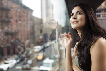 Thoughtful woman looking through glass window - CAVF32827