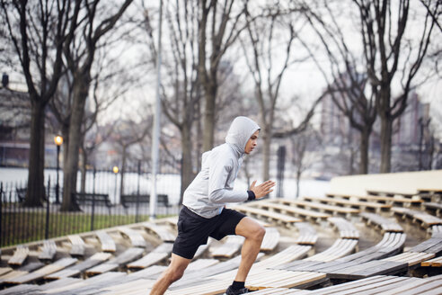 Side view of determined male athlete running at stadium - CAVF32837