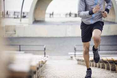 Low section of male athlete running on steps at stadium - CAVF32839