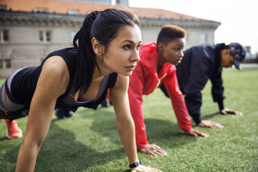 Determined athletes doing push-ups on grassy field - CAVF32857