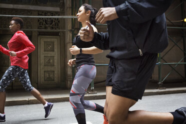 Seitenansicht von entschlossenen Athleten beim Joggen auf einer Stadtstraße - CAVF32867