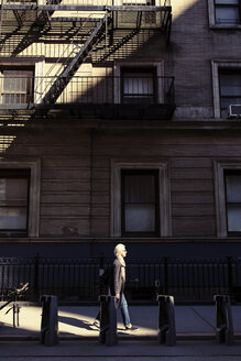 Ältere Frau geht auf dem Bürgersteig vor einem Gebäude - CAVF32883