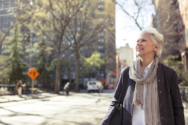 Nachdenkliche ältere Frau lächelt auf der Straße in der Stadt - CAVF32886