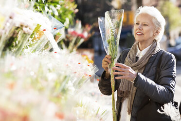 Ältere Frau kauft Blumen an einem Marktstand - CAVF32901