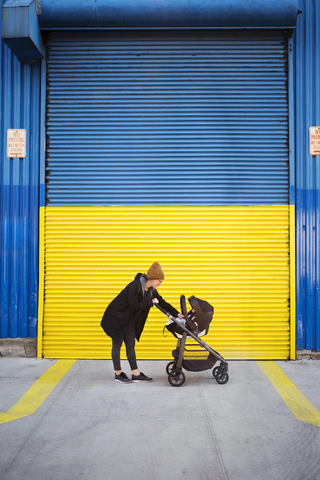 Seitenansicht einer Frau mit Kinderwagen auf der Straße, lizenzfreies Stockfoto