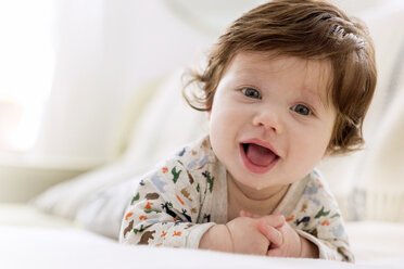 Close-up portrait of cute baby boy lying on bed at home - CAVF32921