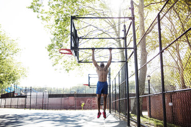 Entschlossener Sportler beim Klimmzug am Basketballkorb - CAVF32945
