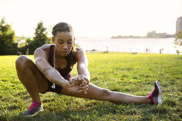 Athlete exercising on grassy field at park against sky - CAVF32950