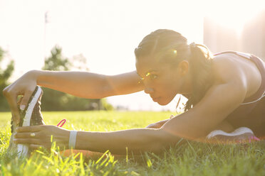 Confident athlete exercising on grassy field at park - CAVF32951