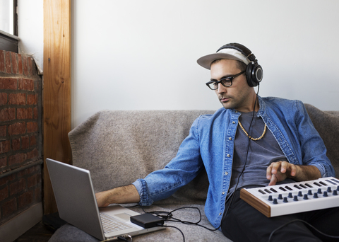 Man using laptop computer with piano at home stock photo