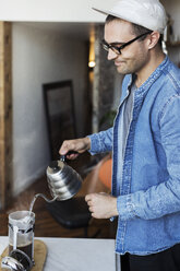 Mann gießt kochendes Wasser in Kaffee zu Hause - CAVF32991
