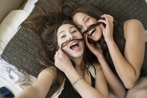 Overhead portrait of female friends making artificial mustache with hair stock photo