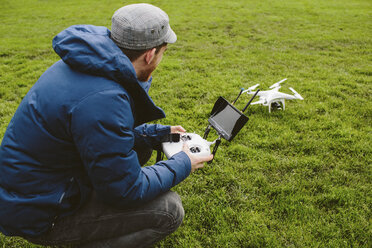 Side view of man flying quadcopter in park - CAVF33057