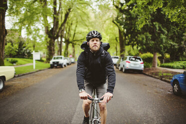 Male commuter riding bicycle on street - CAVF33059