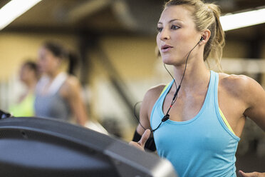 Woman looking away while exercising on treadmill in gym - CAVF33088