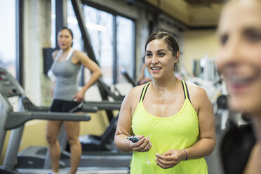 Müde Frauen mit Lehrer, der wegschaut, während sie im Fitnessstudio stehen - CAVF33095