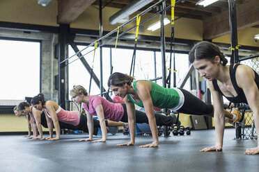 Women bending and exercising with resistance bands in gym - CAVF33109