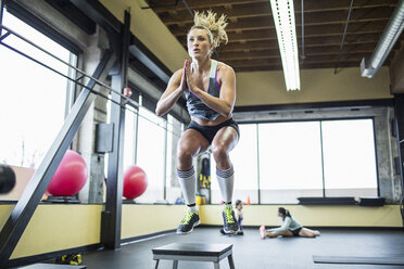 Frau springt über Hocker im Fitnessstudio - CAVF33120