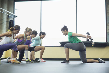 Trainerin leitet Frauen bei Übungen mit Hanteln im Fitnessstudio an - CAVF33126