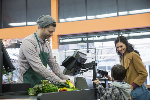 Arbeiter, der eine Rechnung ausstellt, während er mit einem Kunden an der Kasse im Supermarkt steht - CAVF33187