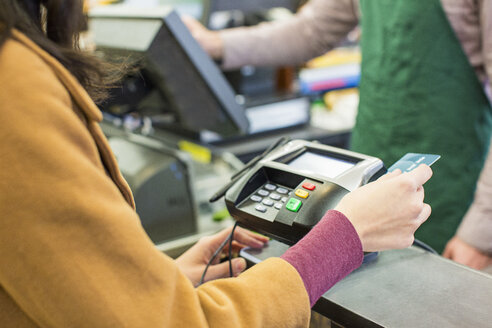 Mittelteil einer Frau, die im Supermarkt ihre Rechnung mit einer Kreditkarte bezahlt - CAVF33194