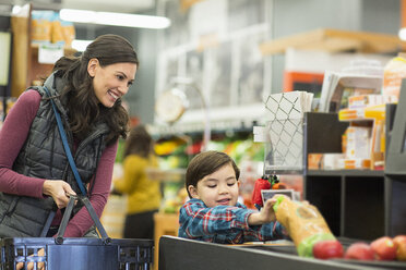 Mutter und Sohn halten Lebensmittel an der Kasse im Supermarkt - CAVF33195