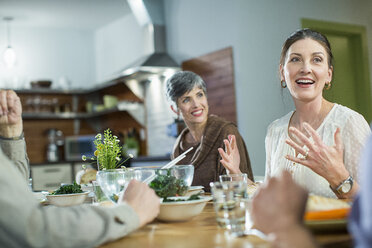 Friends talking while sitting at table during social gathering - CAVF33236