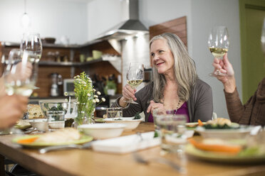 Friends with wineglasses sitting at table during social gathering - CAVF33239