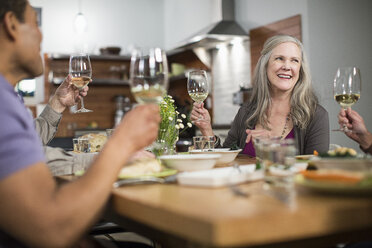 Happy friends with wineglasses sitting at table during social gathering - CAVF33240