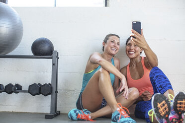 Glückliche Freundinnen nehmen Selfie durch Handy in der Turnhalle - CAVF33262