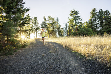 Frau in voller Länge beim Joggen auf einem Weg gegen den Himmel - CAVF33314