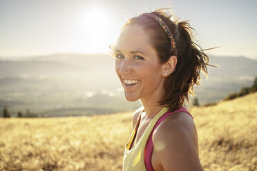 Portrait of smiling woman standing on mountain against clear sky during sunny day - CAVF33320