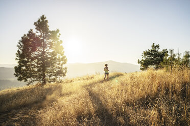 Frau in voller Länge joggt auf Berg gegen Himmel während sonnigen Tag - CAVF33323