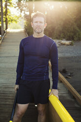 Porträt eines Mannes mit Paddleboard auf der Promenade - CAVF33339