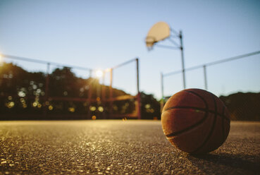 Nahaufnahme eines Basketballs auf dem Boden im Gericht bei Sonnenuntergang - CAVF33380