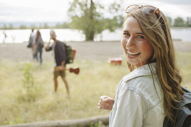 Porträt einer glücklichen Frau mit Rucksack auf einem Feld - CAVF33384