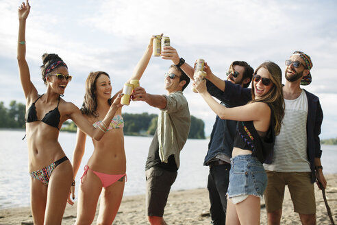 Glückliche Freunde stoßen am Flussufer mit Dosen an - CAVF33399