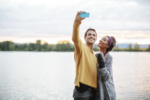 Freunde nehmen Selfie beim Stehen durch den Fluss gegen den Himmel, lizenzfreies Stockfoto