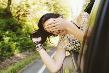 Glückliche Frau, die durch das Fenster schaut, während sie im Auto reist - CAVF33447