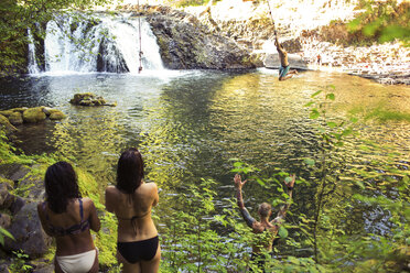 Hohe Winkel Ansicht von Freunden Blick auf Mann schwingt über Fluss im Wald - CAVF33469