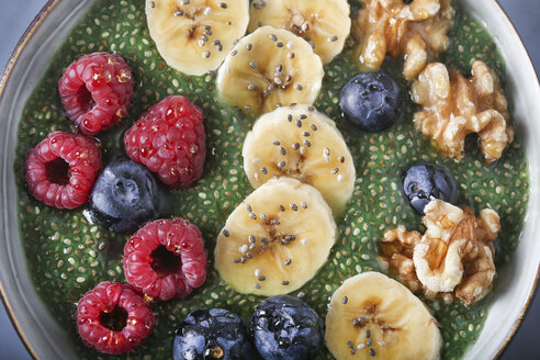 Buddha bowl of green chia pudding with slices of banana, blueberries, raspberries and walnuts - RTBF01143