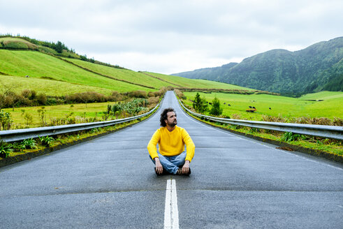 Azoren, Sao Miguel, Mann sitzt auf einer leeren Straße - KIJF01915