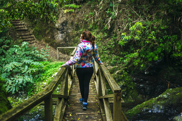 Azoren, Sao Miguel, Frau geht auf einer Holzbrücke durch den Wald - KIJF01921