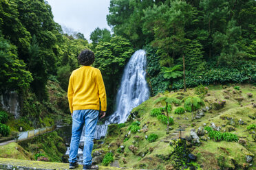 Azoren, Sao Miguel, Rückansicht eines Mannes mit Blick auf einen Wasserfall im Naturpark Ribeira dos Caldeiroes - KIJF01922