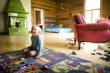 Boy kneeling on multi colored carpet in room - FOLF06603