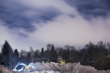 Excavator removing snow next to houses in forest - FOLF06619