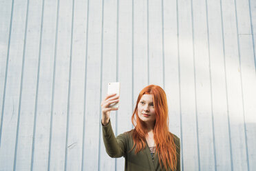 Rothaarige Frau nimmt Selfie gegen weiße Wand - FOLF06628